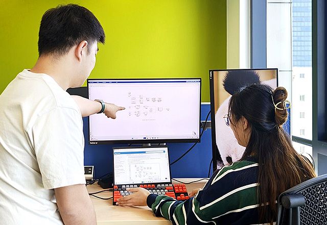 两位 mathworks 员工看着计算机屏幕，其中一人指向屏幕上的特定区域。